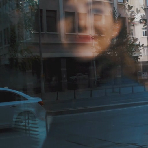 A_reflection_of_a_woman_on_a_building's_glass_window_with_a_car_parked_nearby_ours
