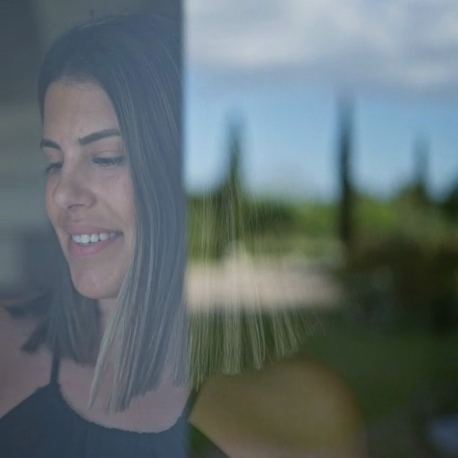 A_smiling_woman_stands_behind_a_window,_reflecting_the_outdoors_ours